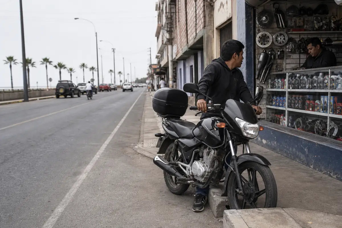 Peru commuter motorcycle rider reviewing aftermarket parts at a Lima neighborhood parts counter